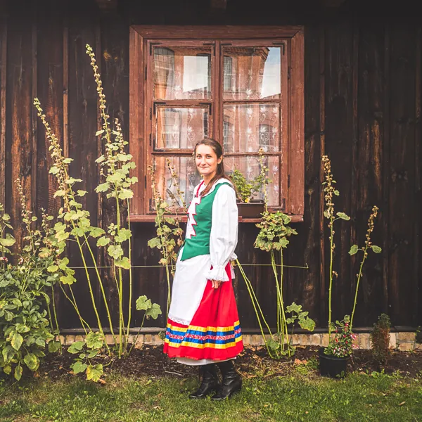 Ania Nowak w ludowym stroju przy drewnianym domu